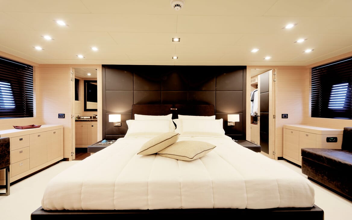 Motor yacht KAWAI master suite with white bed linen, dark wood interiors with soft lighting