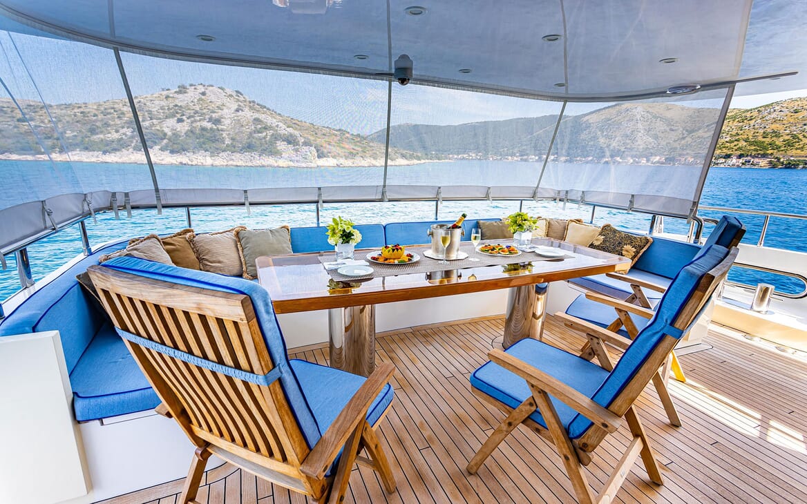 Motor yacht Milaya deck with alfresco dining table and blue seating