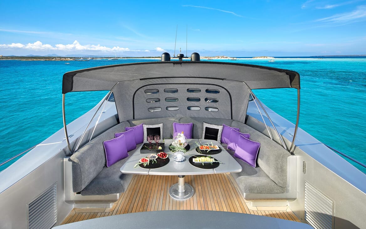 Motor Yacht SHALIMAR II top deck area with grey and purple furnishings, views of turquoise water and alfresco dining area