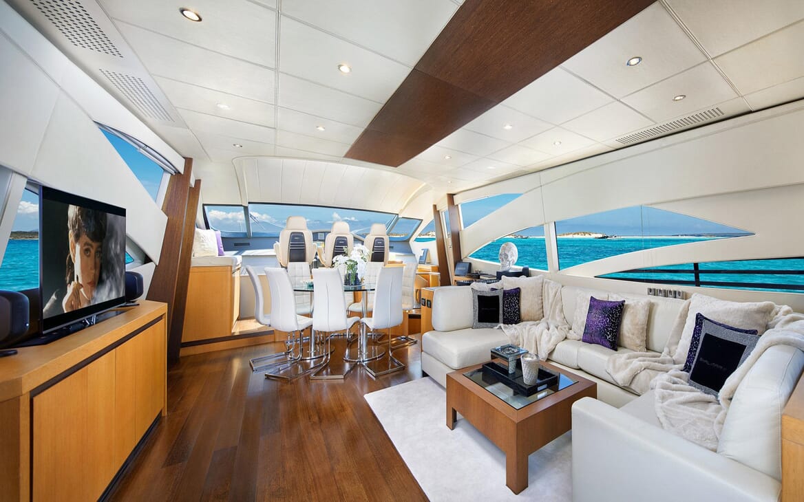 Motor Yacht SHALIMAR II living room with dark wood floors, cream sofa with soft furnishings and views of turquoise water