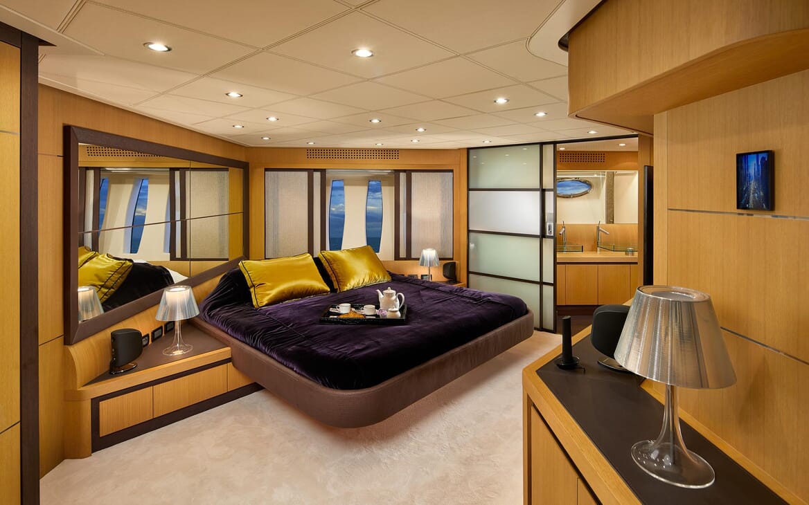 Motor Yacht SHALIMAR II master suite with purple and mustard silk bed linen, mirrored walls and sliding frosted glass door to ensuite