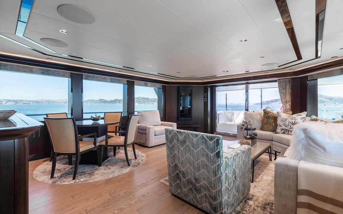 Interior of the 39.62m yacht FIGARO featuring a dining area, living room, and panoramic views of the ocean, focusing on the luxury aesthetic.