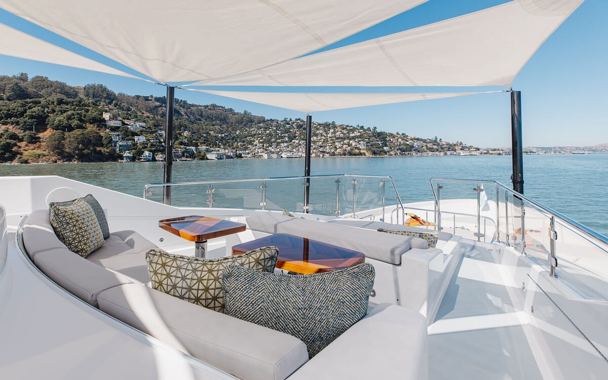 The FIGARO yacht's exterior features a sun deck with seating, tables, and a sunshade. The 39.62m yacht is pictured at sea with a coastal view.