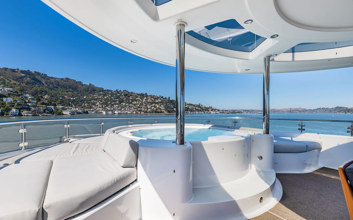 The yacht FIGARO boasts a luxurious exterior with a jacuzzi, seating, and stunning water views. A partially shaded deck provides the perfect setting.