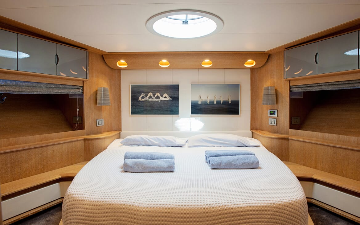 Motor Yacht SLIP AWAY master suite with wood surroundings, skylight and abstract marine artwork