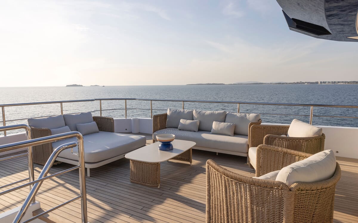 Vista exterior del BEE YACHT con cómodos asientos al aire libre. La imagen muestra una cubierta de teca con sofás y sillas en el mar.