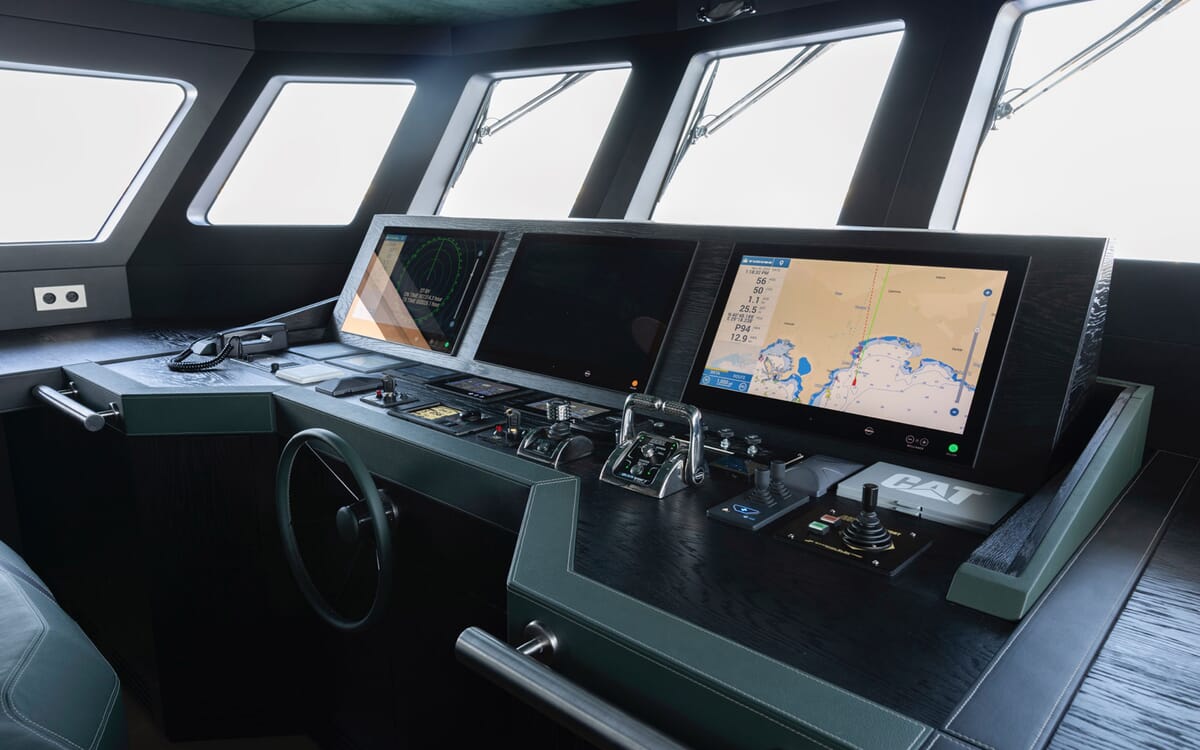 Vista interior del timón del BEE YACHT, con pantallas y controles de navegación. Un primer plano muestra el centro de mando del yate con un interior oscuro.