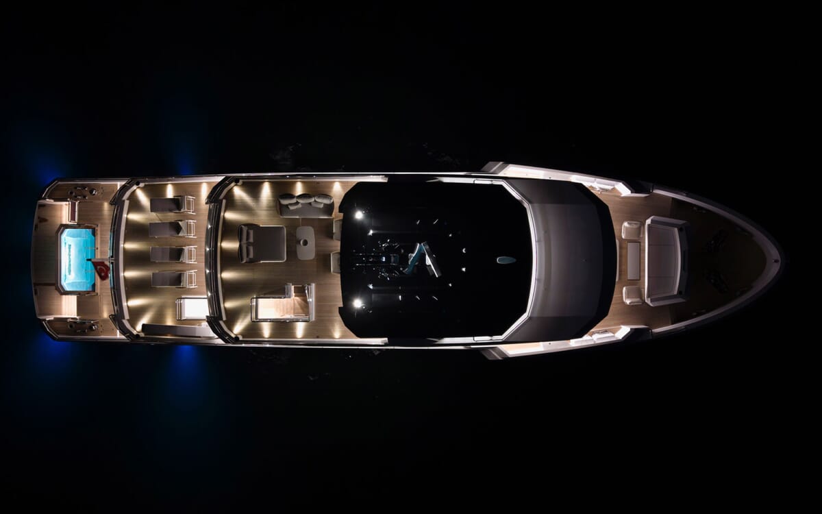 Vista aérea nocturna del BEE YACHT, un yate de lujo de 35,42 m. Incluye una cubierta iluminada, un jacuzzi y zonas para sentarse sobre aguas oscuras.