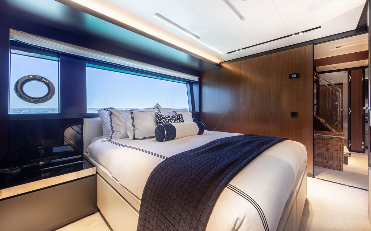 Innenansicht des Schlafzimmers der Yacht LEMON NOT LIME. Zur Ausstattung gehören ein Bett, ein Bullauge mit Blick auf den Ozean und eine Holzverkleidung.