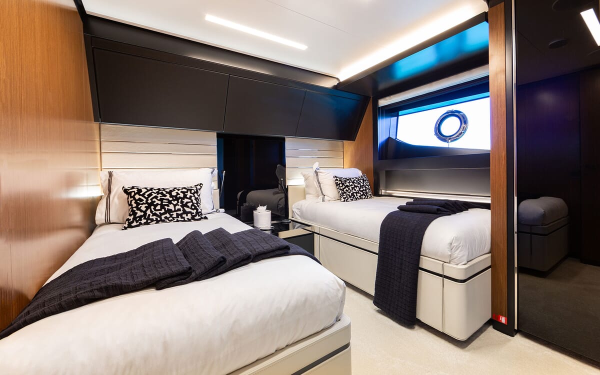 Innenansicht der Jacht LEMON NOT LIME. Das Bild zeigt eine luxuriöse Kabine mit zwei Betten, modernem Design und einem Bullauge.