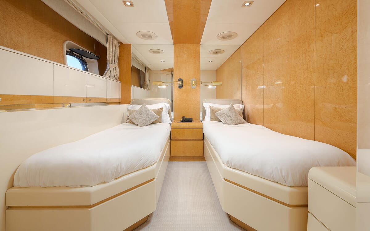 Das Innere der LADYSHIP-Yacht zeigt eine Gästekabine mit zwei Einzelbetten. Mit heller Holzverkleidung, Spiegeln und neutraler Bettwäsche.