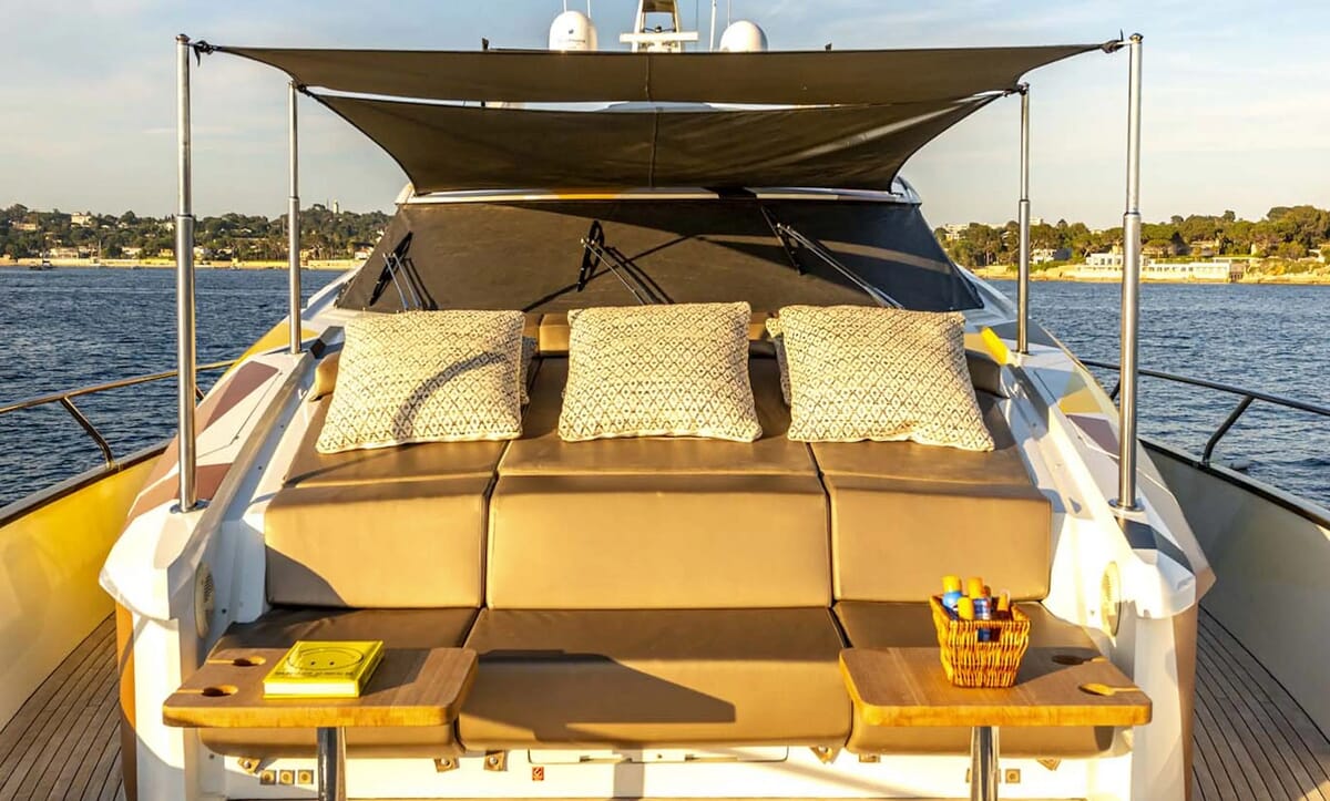 Das hintere Deck der QUANTUM-Yacht mit bequemen Sitzgelegenheiten mit Kissen, Sonnenschirm und Beistelltischen mit Zubehör, auf See.