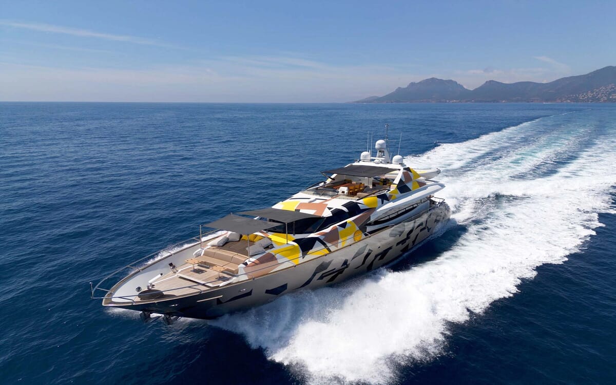 Luftaufnahme der QUANTUM-Yacht (28,41 m) auf See, die sich durch ein einzigartiges Tarnmuster und offene Decksbereiche auszeichnet.