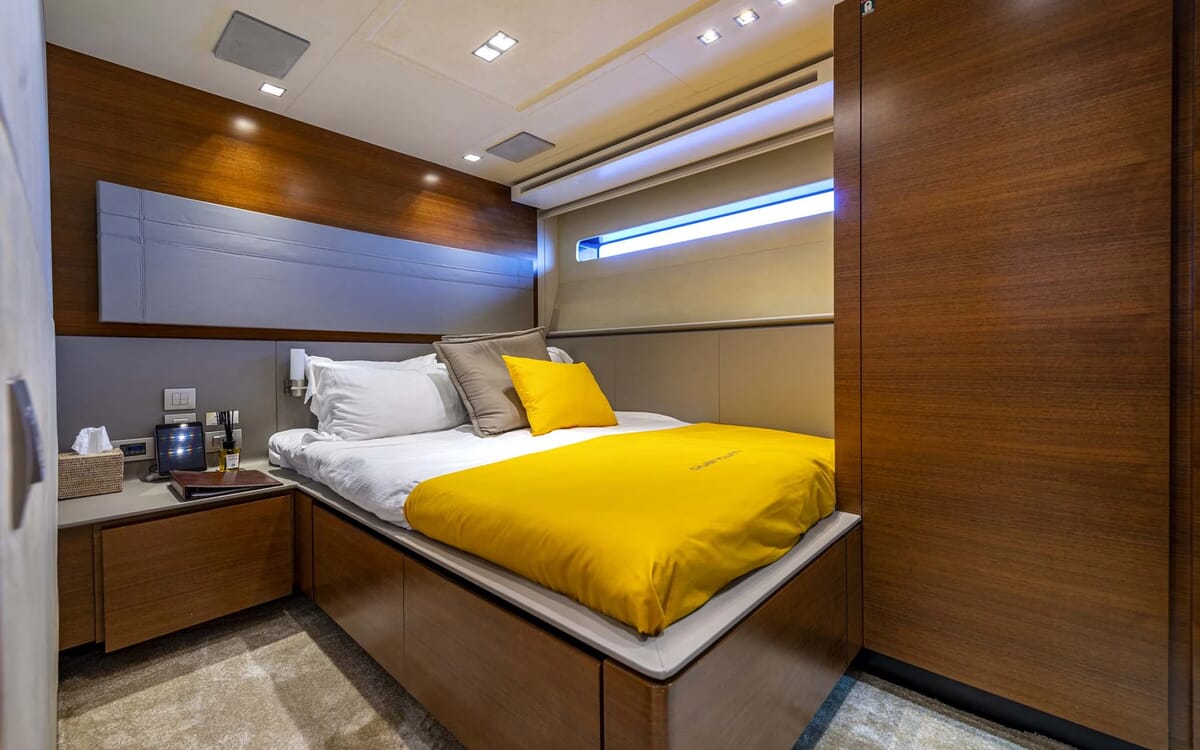 Das Innere der QUANTUM-Yacht mit einem Schlafzimmer mit einem Doppelbett, gelber Bettwäsche und Holzschränken.