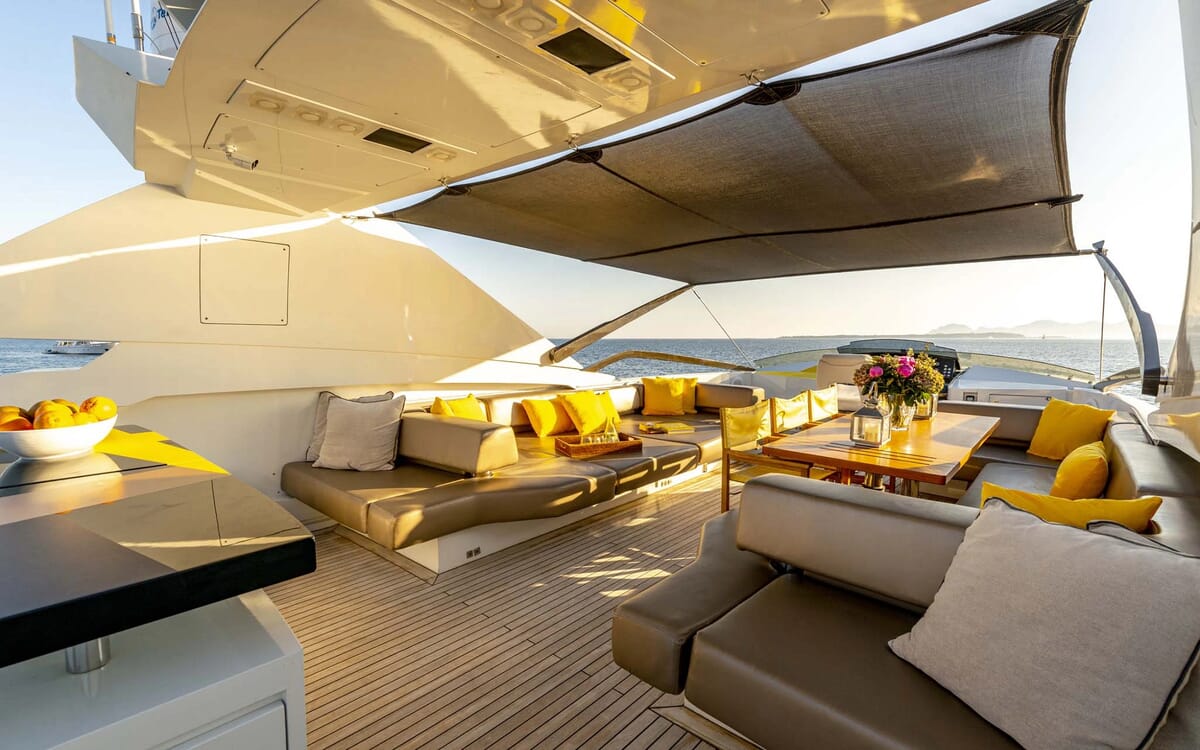 Das Deck der QUANTUM-Yacht auf See mit Sonnenschirm, Sitzgelegenheiten und Holztisch zum Entspannen. Die 28,41 m lange Yacht bietet einen hohen Außenkomfort.