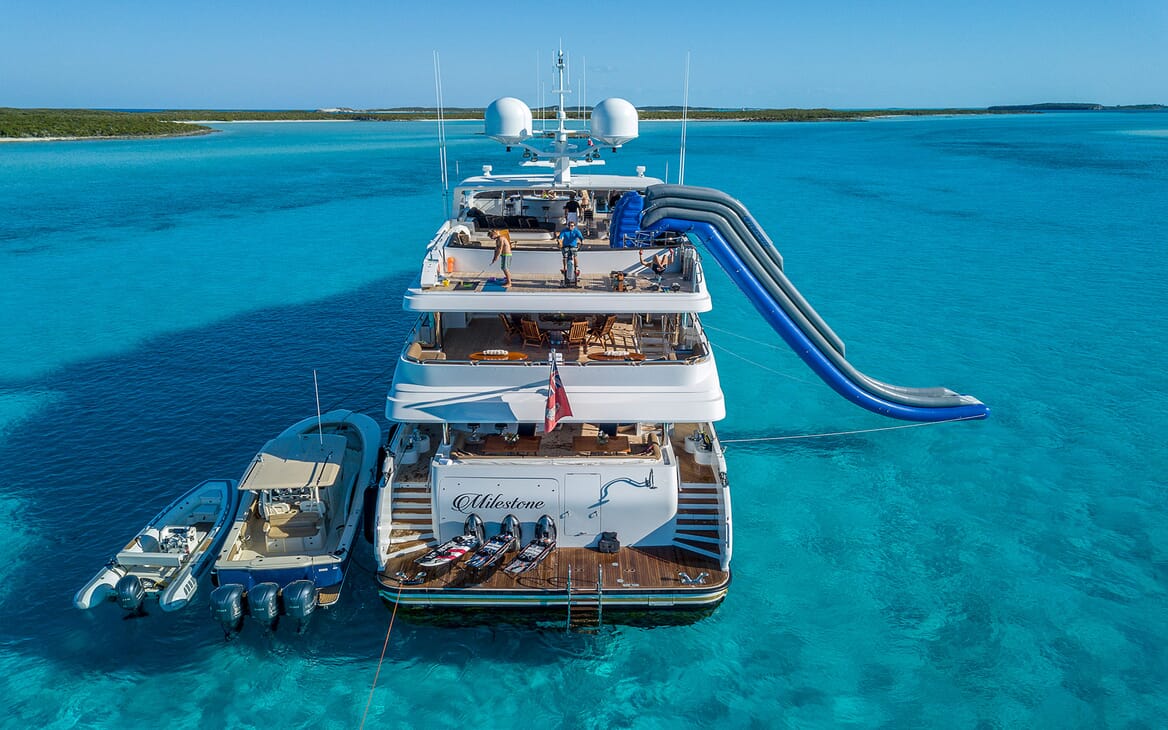 Motor yacht MILESTONE aft aerial shot on turquoise water and tender