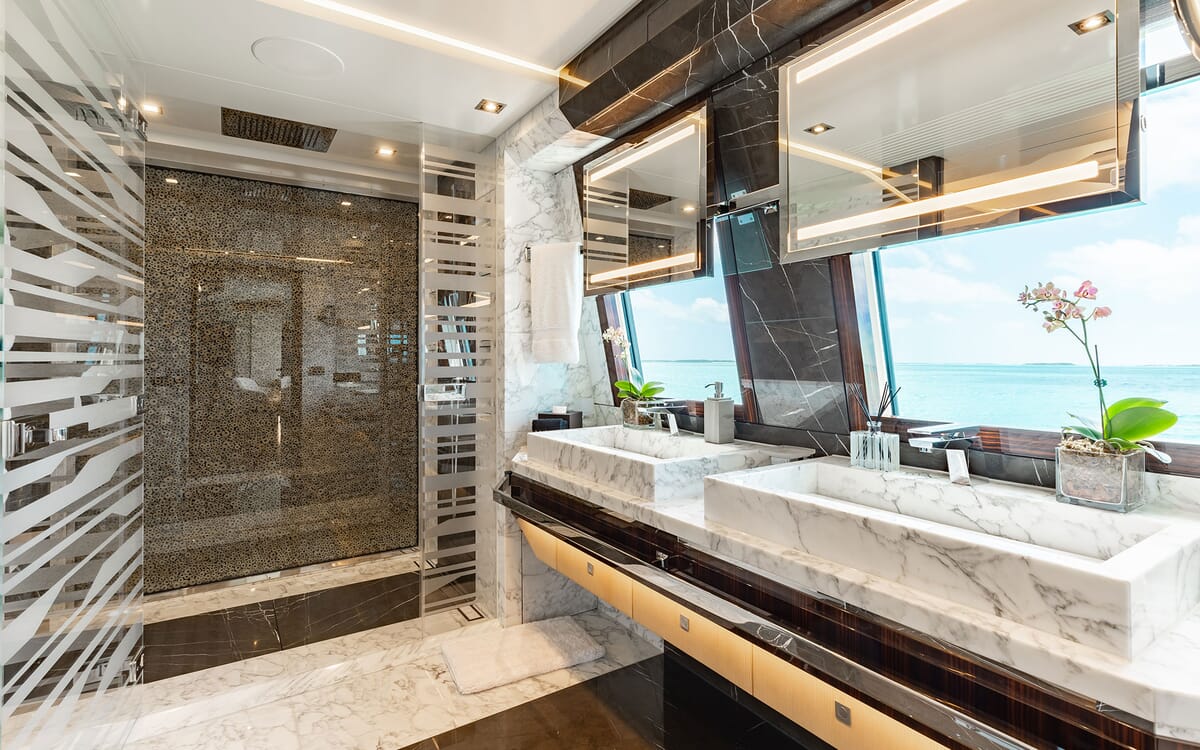Luxuriöses Badezimmer auf der 46,71 m langen Yacht ODYSSEA. Mit Marmorwaschbecken, einer Dusche und einem großen Fenster mit Blick aufs Meer.