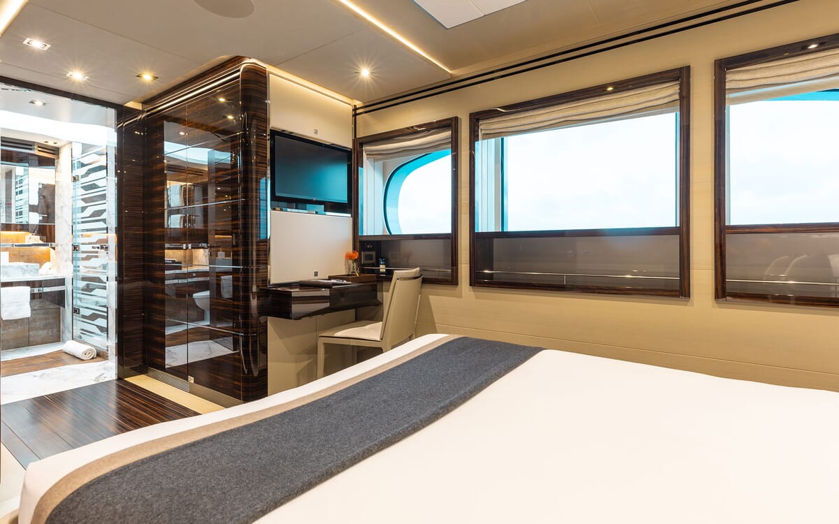Das Innere der ODYSSEA Yacht zeigt ein luxuriöses Schlafzimmer mit einem Schreibtisch, großen Fenstern und einem begehbaren Badezimmerbereich.